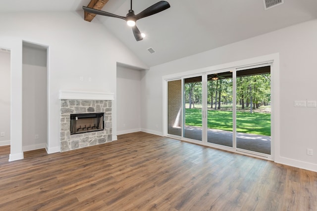 unfurnished living room featuring beam ceiling, ceiling fan, a stone fireplace, and wood-type flooring