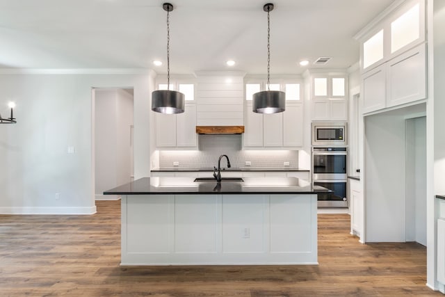 kitchen with stainless steel appliances, white cabinets, hanging light fixtures, dark countertops, and glass insert cabinets