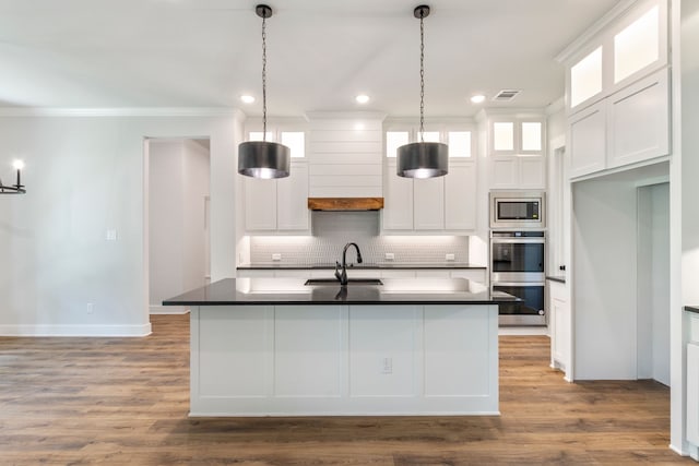 kitchen with stainless steel appliances, a sink, dark countertops, visible vents, and crown molding