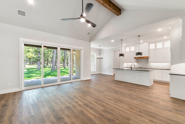 interior space with a sink, white cabinetry, open floor plan, dark countertops, and glass insert cabinets