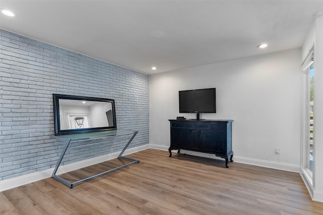 living area with recessed lighting, baseboards, brick wall, and wood finished floors