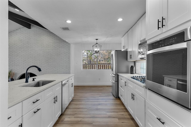 kitchen featuring sink, white cabinets, brick wall, and stainless steel appliances