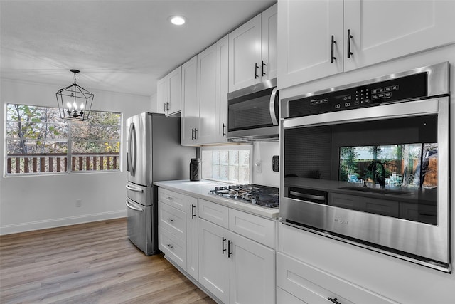 kitchen with an inviting chandelier, white cabinetry, a wealth of natural light, and stainless steel appliances