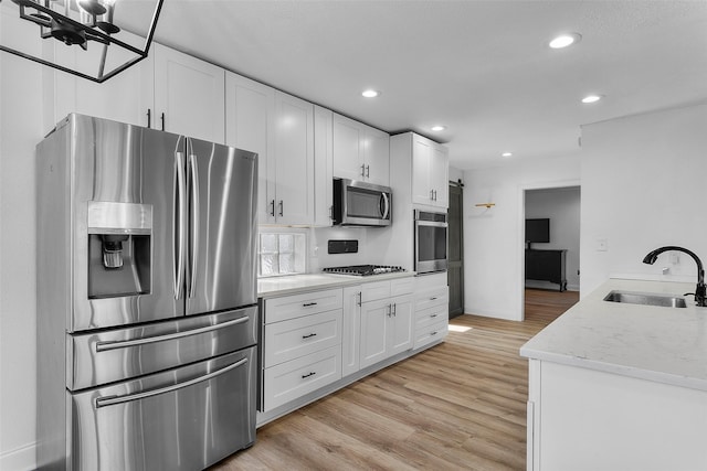 kitchen with recessed lighting, light wood-style flooring, appliances with stainless steel finishes, white cabinets, and a sink