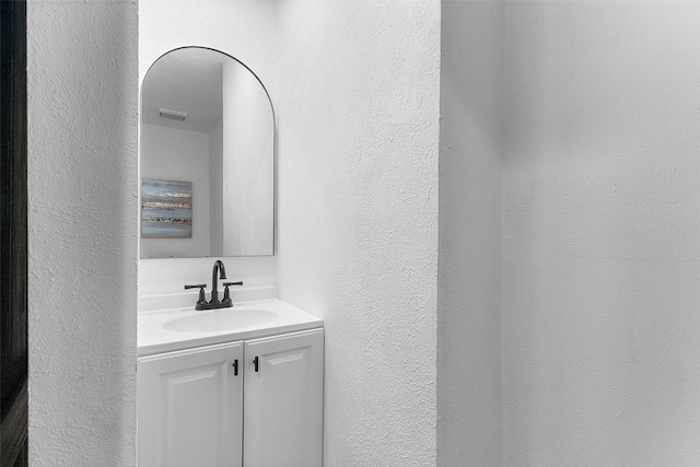 bathroom featuring a textured wall, visible vents, and vanity