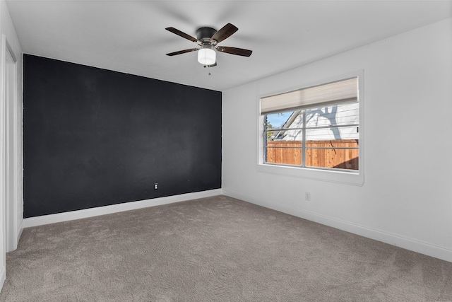 carpeted spare room with ceiling fan and baseboards