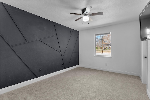 spare room featuring light carpet, ceiling fan, a textured ceiling, and baseboards