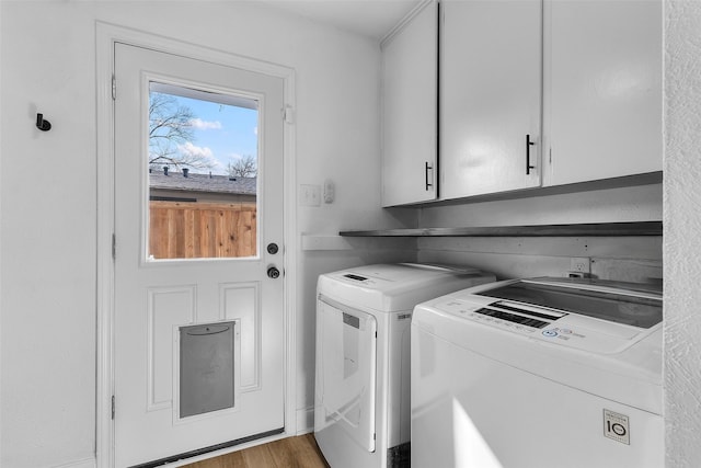 washroom featuring cabinet space, washing machine and clothes dryer, and wood finished floors