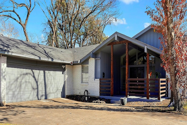 view of side of home with a garage, concrete driveway, board and batten siding, and brick siding