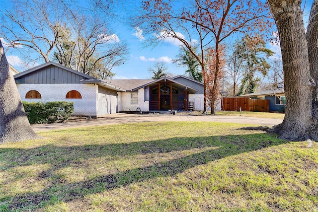 view of front of home featuring concrete driveway, an attached garage, fence, a front lawn, and brick siding