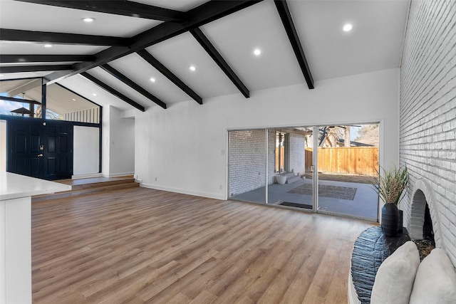 unfurnished living room with light hardwood / wood-style flooring, beam ceiling, and high vaulted ceiling