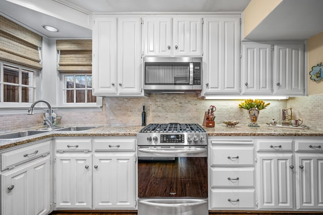 kitchen featuring decorative backsplash, sink, stainless steel appliances, white cabinets, and light stone counters