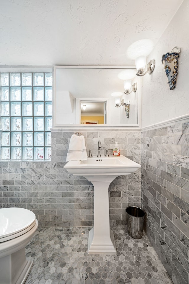 bathroom with toilet and tile walls