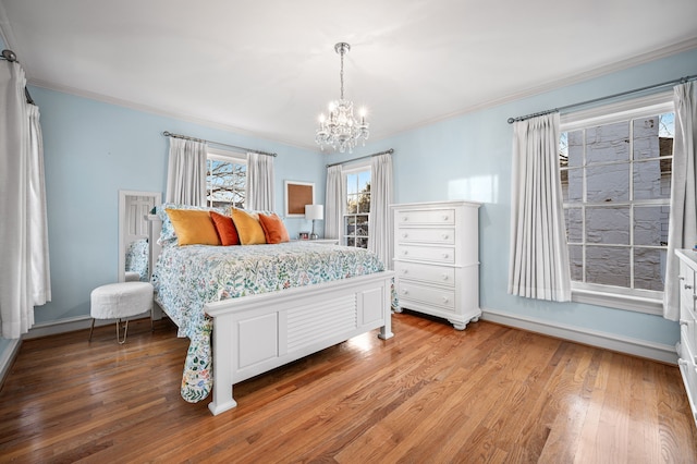 bedroom featuring a notable chandelier, crown molding, and light hardwood / wood-style flooring