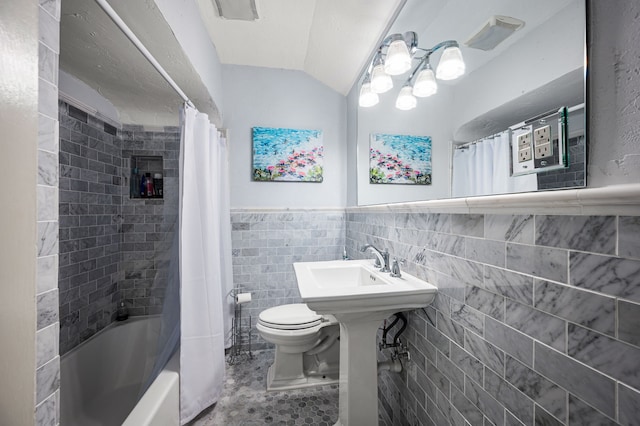 full bathroom featuring tile patterned floors, shower / tub combo, tile walls, toilet, and vaulted ceiling