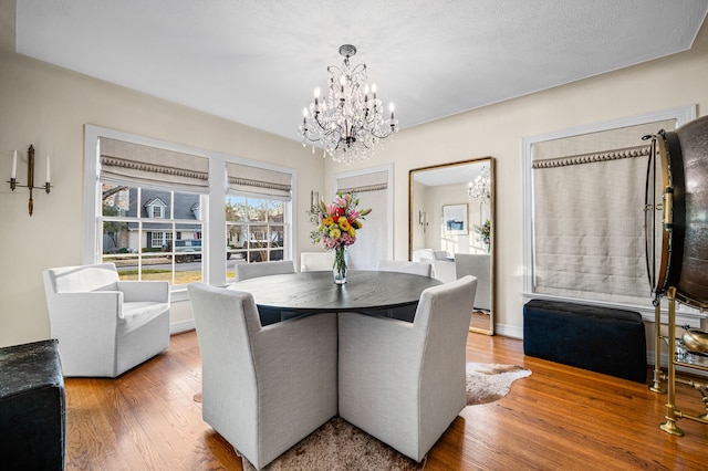 dining space with a chandelier, a textured ceiling, and hardwood / wood-style flooring