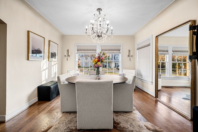 dining room featuring a textured ceiling, dark wood-type flooring, and a notable chandelier