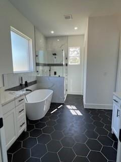 bathroom with tile walls, plus walk in shower, vanity, and a healthy amount of sunlight