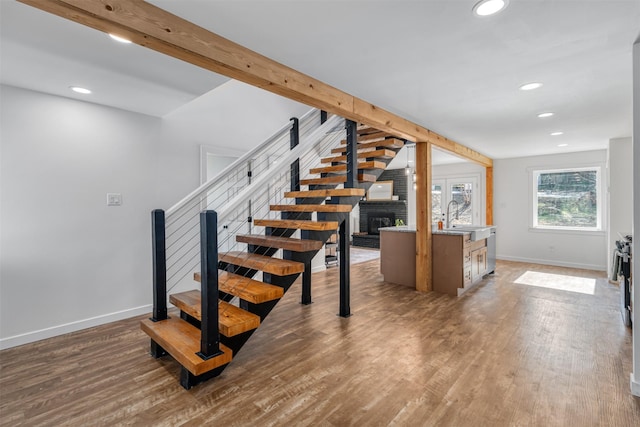 staircase with beamed ceiling, sink, a fireplace, and hardwood / wood-style floors