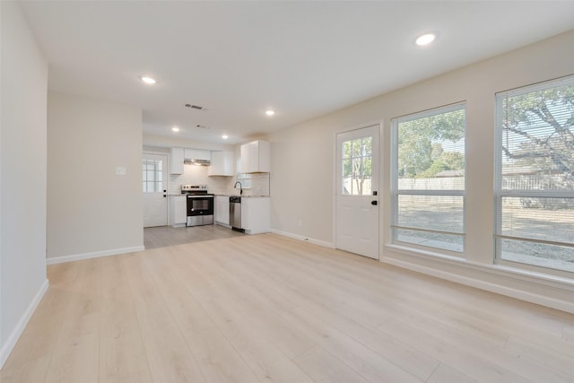 unfurnished living room featuring sink and light hardwood / wood-style floors