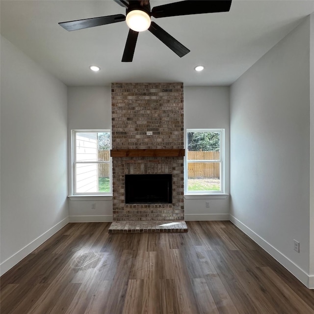 unfurnished living room featuring a brick fireplace, dark wood-type flooring, and ceiling fan