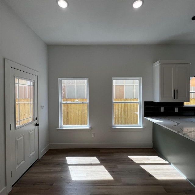 kitchen with dark hardwood / wood-style floors, white cabinetry, backsplash, and light stone counters