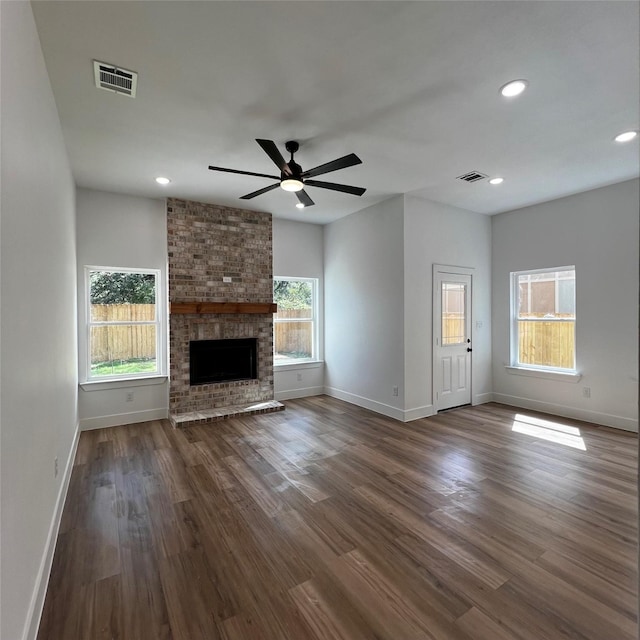 unfurnished living room with ceiling fan, a brick fireplace, and dark hardwood / wood-style floors