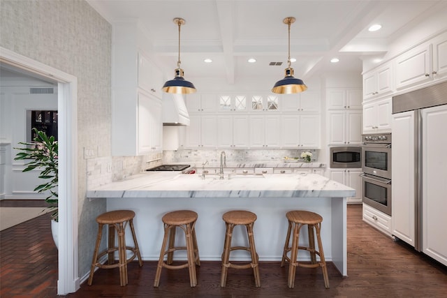 kitchen with beam ceiling, white cabinetry, kitchen peninsula, and built in appliances