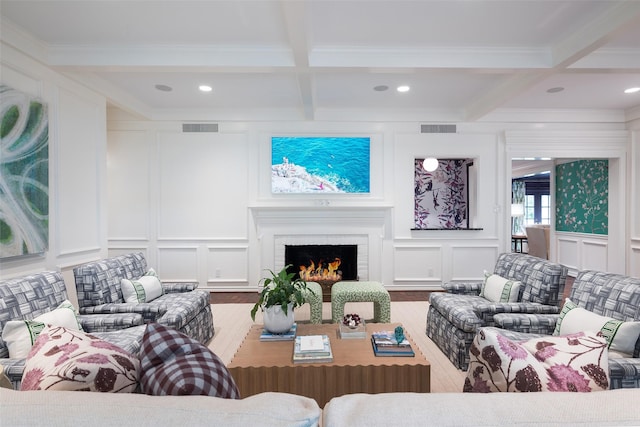 living room featuring a fireplace, beam ceiling, wood-type flooring, coffered ceiling, and ornamental molding