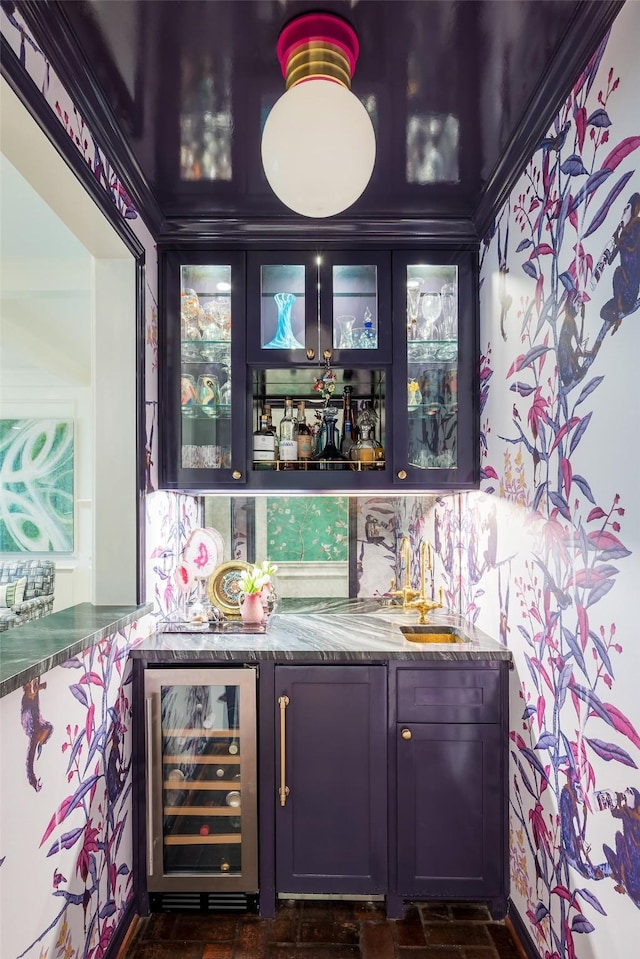 bar with beverage cooler, backsplash, dark stone counters, and sink