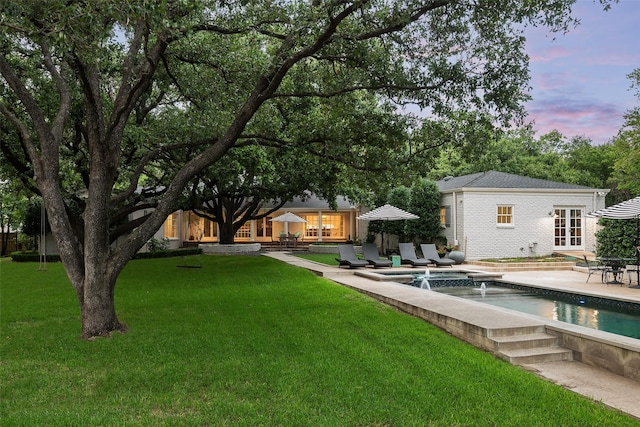 yard at dusk featuring french doors and a patio