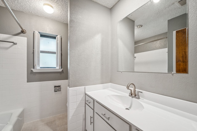 bathroom featuring shower / bathtub combination, vanity, tile walls, and a textured ceiling