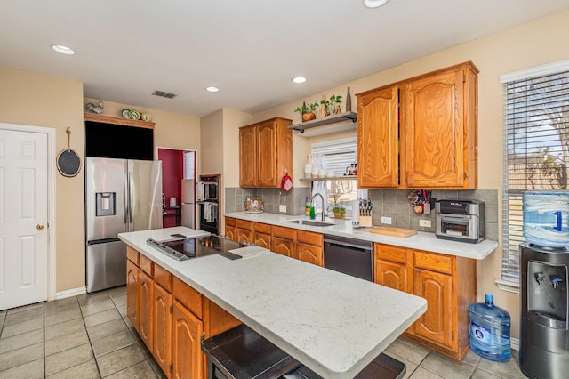 kitchen with backsplash, light tile patterned flooring, a kitchen island, black appliances, and sink