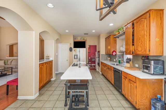 kitchen featuring black appliances, a kitchen island, decorative backsplash, sink, and light tile patterned floors