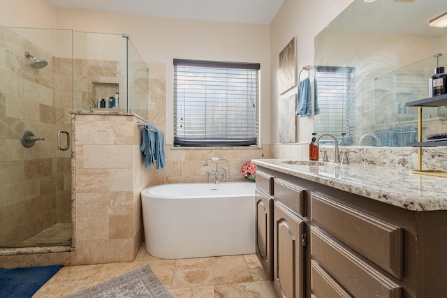 bathroom with tile walls, vanity, and independent shower and bath