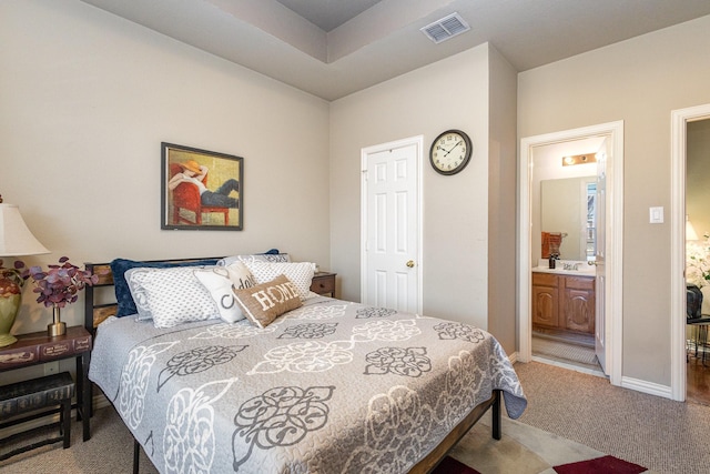 carpeted bedroom with sink and ensuite bathroom