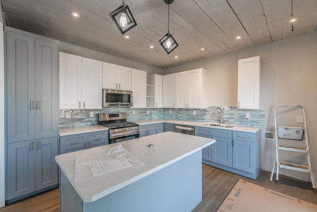 kitchen featuring white cabinetry, stainless steel appliances, decorative light fixtures, a kitchen island, and sink