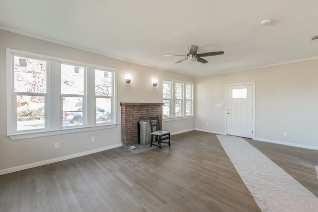 unfurnished living room with ceiling fan, dark hardwood / wood-style flooring, crown molding, and a brick fireplace