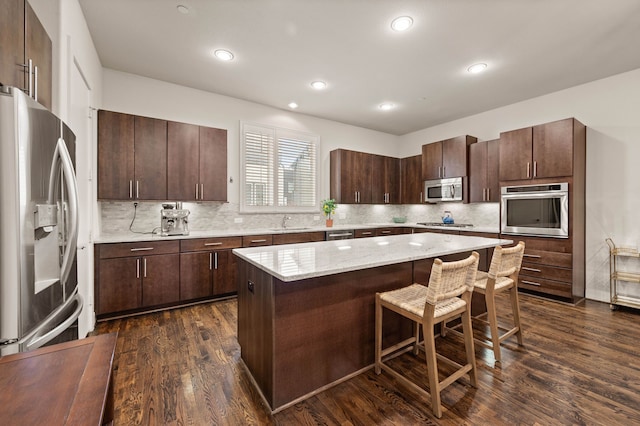 4211 Rawlins St Unit 733, Dallas, TX 75219 - kitchen with stainless steel appliances, a sink, dark wood finished floors, backsplash, and a center island