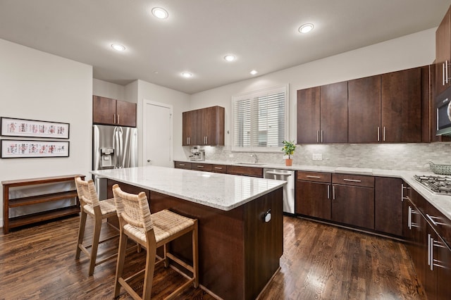 4211 Rawlins St Unit 733, Dallas, TX 75219 - kitchen featuring stainless steel appliances, a breakfast bar, a kitchen island, dark wood-type flooring, and recessed lighting
