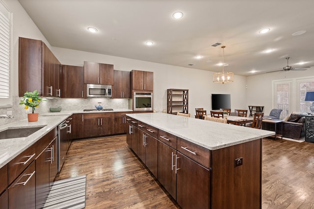 kitchen featuring a kitchen island, dark wood-style flooring, stainless steel appliances, and a sink