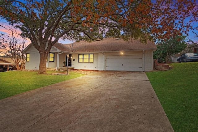 ranch-style house with a garage and a lawn