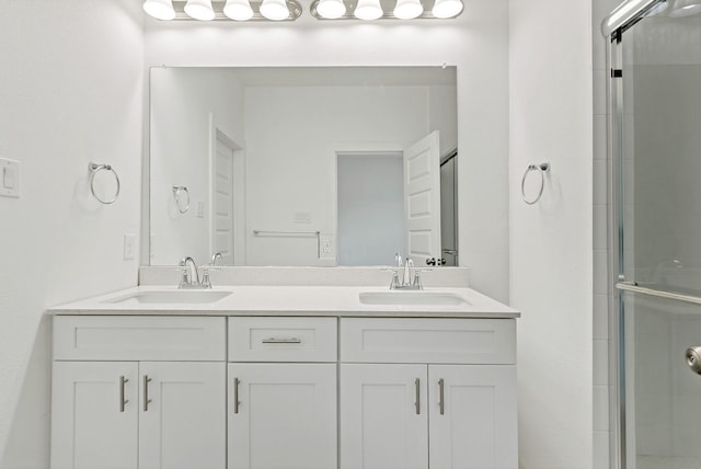 bathroom featuring a shower with shower door and vanity