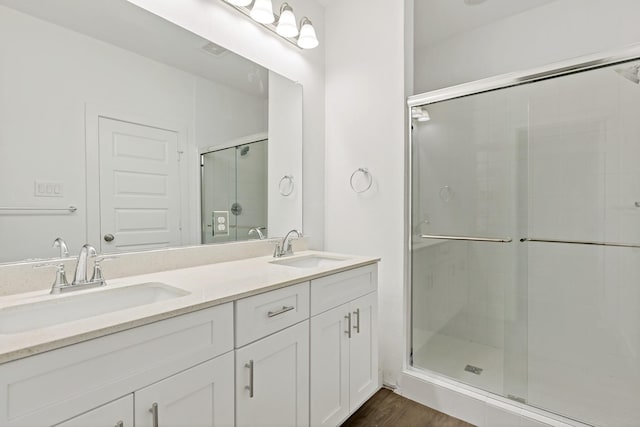 bathroom featuring wood-type flooring, a shower with door, and vanity