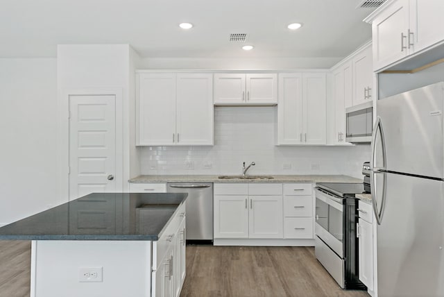 kitchen featuring a kitchen island, sink, white cabinetry, light hardwood / wood-style flooring, and appliances with stainless steel finishes