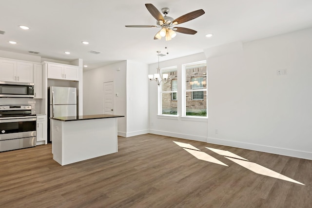 kitchen with white cabinetry, appliances with stainless steel finishes, decorative light fixtures, dark hardwood / wood-style flooring, and ceiling fan with notable chandelier