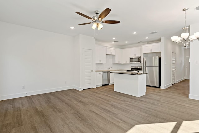 kitchen featuring white cabinetry, stainless steel appliances, light wood-type flooring, hanging light fixtures, and a kitchen island