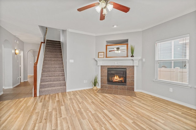 unfurnished living room with ceiling fan, ornamental molding, light hardwood / wood-style floors, and a tile fireplace