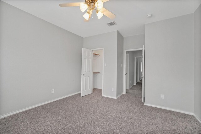 unfurnished bedroom featuring ceiling fan, carpet flooring, a closet, and a walk in closet