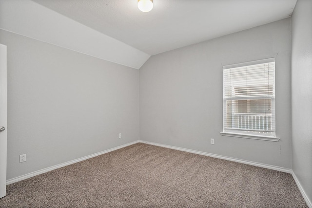 carpeted spare room with vaulted ceiling